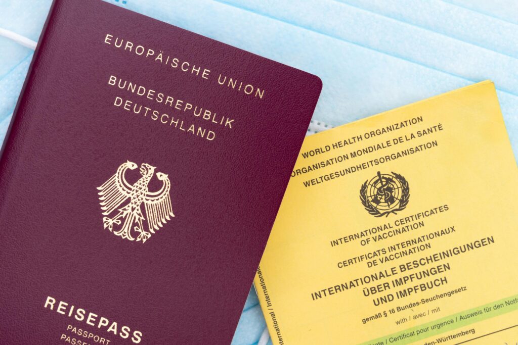 HOME 10 Close-up of a German passport, vaccination card, and face mask, symbolizing travel and health documentation.